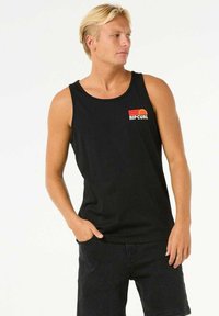 Schwarzes Tanktop aus Baumwolle mit Rundhalsausschnitt und kleinem, mehrfarbigem Rip Curl-Logo auf der Brust, kombiniert mit dunklen Shorts.