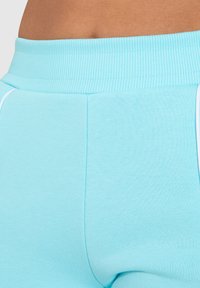 Lichtblauwe sportshorts met een geribde tailleband, featuring een gladde textuur, subtiele naden en witte zijaccenten.