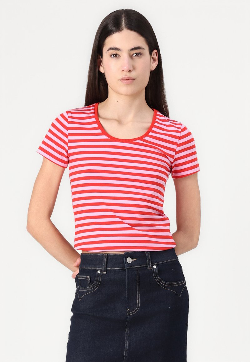 T-shirt à manches courtes rayé rouge et rose avec un col rond, fabriqué en tissu doux. Associé à une jupe en denim foncé.