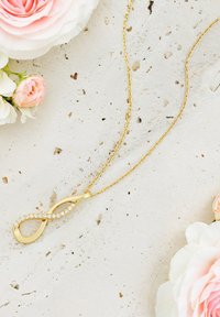 Collana d'oro con pendant infinito, adornata con strass trasparenti. La catena è delicata con un design a maglia standard.