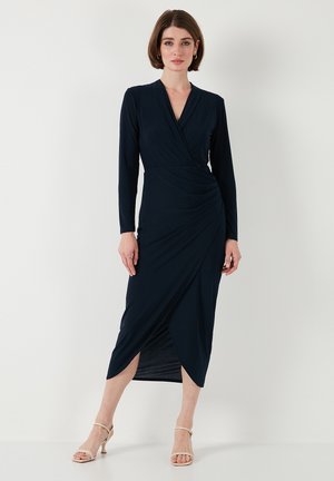 Navy blue, long-sleeved dress featuring a wrap design, ruched detailing at the waist, and a knee-length split. Smooth, stretchy fabric.