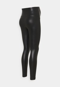Svarta högmidjade leggings i glänsande material, med en strömlinjeformad design och nära passform, slät yta och utan synlig hårdvara.
