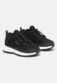 Zapatillas negras con una textura áspera, cuentan con cordones elásticos, cuello acolchado y una media suela blanca. Suela negra resistente para mayor agarre.
