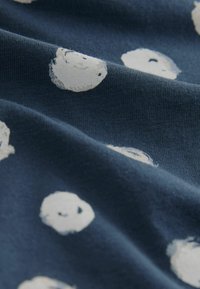 Cotton fabric featuring a navy background with evenly spaced white circular patterns. The texture is smooth and slightly stretched.