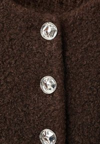 Tissu texturé marron avec trois boutons argentés brillants. Le tissu semble doux et duveteux, ajoutant de la profondeur à l'attrait visuel du matériau.