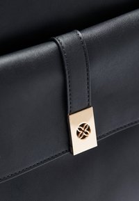 Black leather bag featuring a sleek design, smooth texture, and a gold clasp with a floral pattern detail.