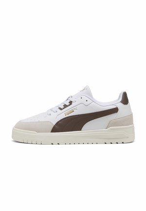 Hvid lavsko med beige tåhætte, brun sidestribe, hvide snørebånd og beige sål. Puma-logo i guld på siden og tungen.
