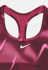 Športový crop top v tmavo ružovej a fuchsiovej farbe s diagonálnymi pruhmi. Obsahuje dizajn s pretekárskym chrbtom a malé biele logo Nike blízko stredu.