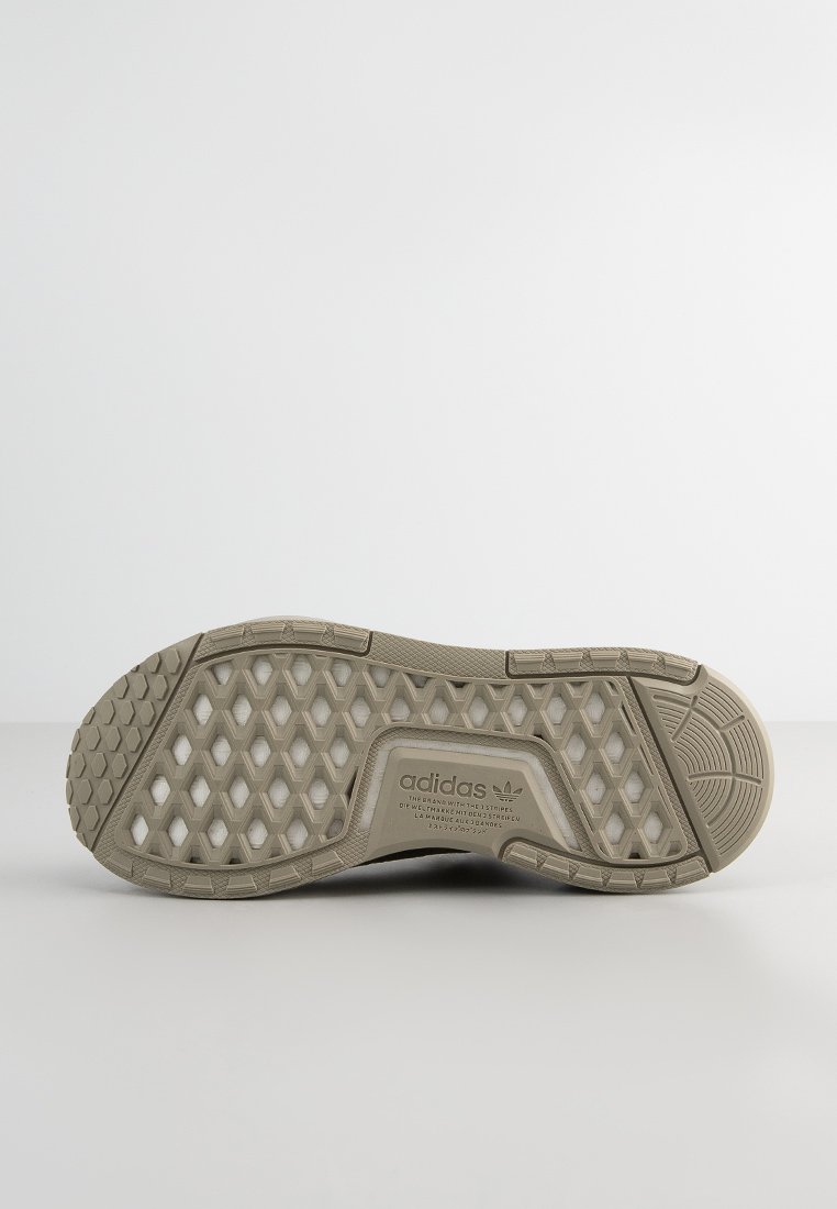 Suela de zapatilla Adidas beige con patrón de relieve hexagonal y logo de Adidas con texto multilingüe en el centro.