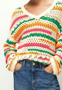 Strickpullover mit V-Ausschnitt in Creme, versehen mit bunten Streifen in Pink, Orange und Grün, offen gearbeiteten Textur und gerippten Bündchen.