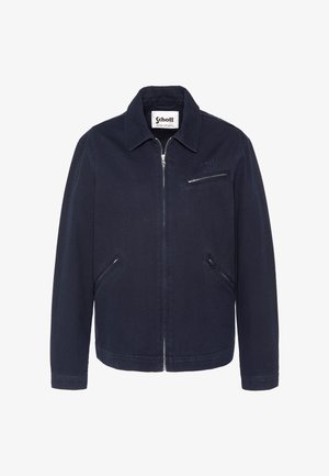 Veste zippée bleu marine avec col, trois poches zippées, logo Schott brodé sur la poitrine et étiquette à l'intérieur du col.