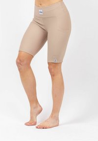 Beige fietshorts met een geribbelde textuur, hoge tailleband en zijzakken; heeft een klein label aan de zoom.