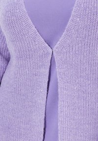 Stickad cardigan i ljus lavendel med V-ringning, texturerad väv och små paljetter. Har en knäppning fram.