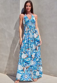 Maxi kjole i blå med blomster mønster, halterneck, samlet front, flydende silhuet, letvægtsstof og ankel-længde design.