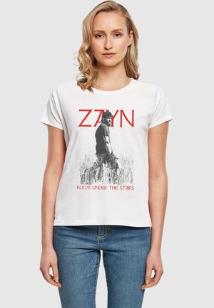 Valkoinen puuvillapaita, jossa on mustavalkoinen grafiikka miehestä, tekstillä "ZAYN" punaisella ja "ROOM UNDER THE STAIRS" alla tyylitellyllä fontilla.