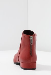 Rote Leder-Ankle-Boots mit abgerundeter Zehenpartie, seitlichem Reißverschluss und glatter Oberfläche. Niedriger Blockabsatz für Stabilität.