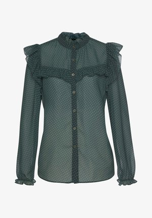 Blusa verde translúcida con lunares blancos, escote con volantes, botones en la parte delantera y mangas largas con puños elásticos. Textura suave.