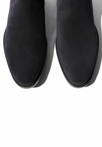 Schwarze Wildleder-Stiefeletten mit spitzem Schuhkopf, glatter Textur und dezentem Stitching. Leichtes Design mit einer schmalen, runden Sohle.