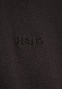 Czarna tkanina z subtelnym, czarnym haftem słowa „HALO” na środku powierzchni.