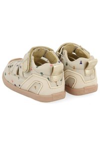 Sandalias infantiles beige con estampados florales, cintas de Velcro y suela de goma. Presentan una textura suave y un diseño de punta redondeada.