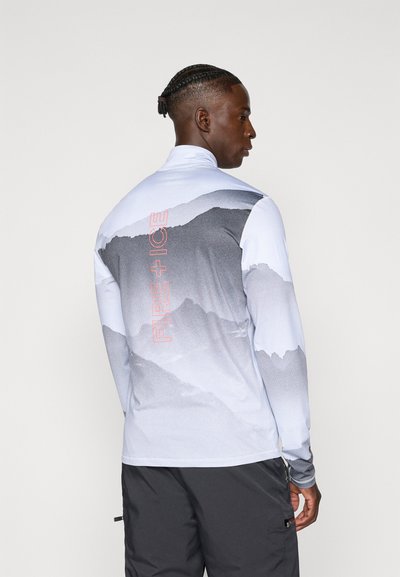 Camiseta de manga larga color azul claro con gráfico de montaña en tonos de gris. Cuenta con el texto rojo "FIRE + ICE" en la parte posterior. Ajuste atlético y suave.