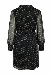 Czarna sukienka w białe groszki, z długimi przezroczystymi rękawami, kołnierzykiem i taliowaniem oraz rozcięciem po boku dla dodatkowego detalu.