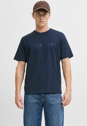 Námornícky modré bavlnené tričko s jemne embosovaným logom "JACK & JONES PREMIUM" na prednej strane. Krátke rukávy a klasický strih.
