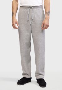 Pantalones de chándal grises con textura de espiga, cinturilla elástica, cordón y corte relajado, combinados con mocasines negros.