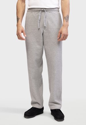 Grey sweatpants with a herringbone texture, elastic waistband, drawstring, and relaxed fit, paired with black loafers.