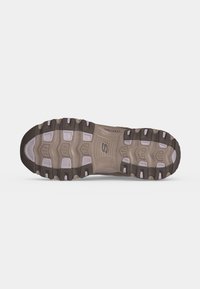 Σόλα παπουτσιού Skechers με ανθεκτικό πέλμα σε μπεζ και σκούρες καφέ αποχρώσεις σε απλό λευκό φόντο.