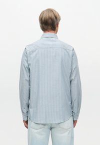 Ανοιχτό μπλε πουκάμισο με ρίγες, κανονικό γιακά και μακριά μανίκια, με καμπυλωτό στρίφωμα και κουμπωτές μανσέτες, φτιαγμένο από μαλακ�ό ύφασμα.