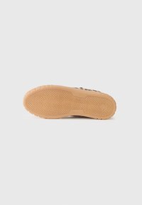 Sole di una sneaker, realizzata in gomma marrone chiaro con un motivo a spina di pesce testurizzato, progettata per aderenza e durata.
