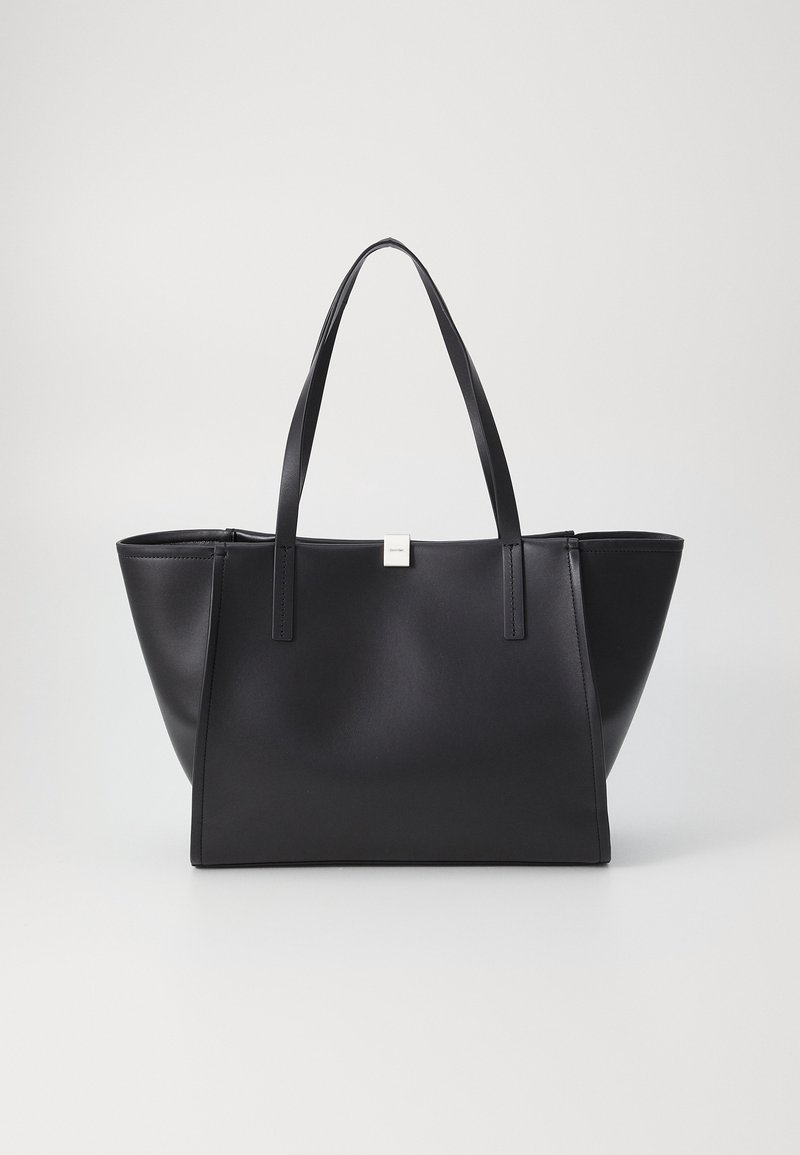 Sac fourre-tout rectangulaire en cuir noir avec deux bretelles d'épaule et un petit logo carré argenté au centre avant.