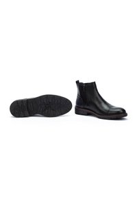 Botas de tobillo de cuero negro con punta redondeada, cremallera lateral, suela de goma texturizada y costura roja en contraste en el canto.