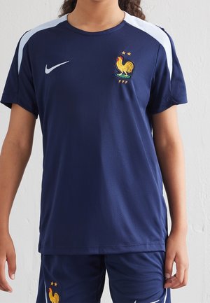 Navy blue soccer jersey with short sleeves, featuring a white Nike logo and embroidered rooster emblem with two stars. Textured fabric.