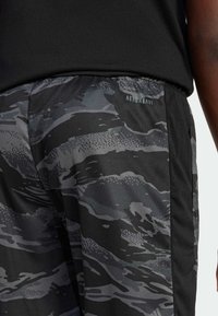 Grå kamouflage-idrottsshorts med svarta sidor, med resårmidja och "AEROREADY"-logo på vänster sida.