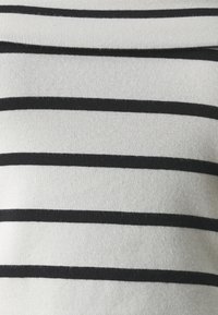 Triibuline pullover, millel on vahelduvad laiad mustad ja valged horisontaalsed jooned, pehme tekstuur, ribidega kangas ning istuv kaelus.