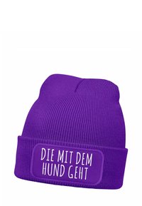 Purple knit beanie with a folded cuff. Features a rectangular patch with white text reading "DIE MIT DEM HUND GEHT." Soft texture, ribbed design.