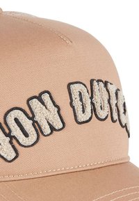 Gorra de béisbol beis con bordado texturizado blanco de "Von Dutch" contorneado en negro en la parte frontal. Tela suave con visera curvada.