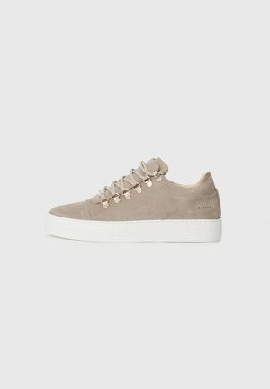 Baskets en daim beige avec semelle en caoutchouc blanc, dotées d'œillets en métal et de lacets plats. Design minimaliste avec bout arrondi et détail de la marque sur le talon.