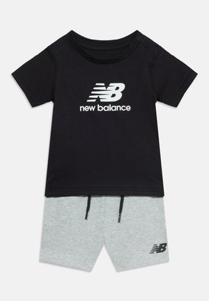 Μαύρο κοντομάνικο μπλουζάκι New Balance με λευκό λογότυπο, συνδυασμένο με ανοιχτό γκρι σορτς που έχει μαύρα κορδόνια και μικρό μαύρο λογότυπο.