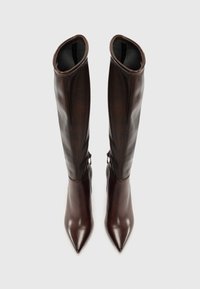 Botas de cuero marrón hasta la rodilla con un diseño de punta afilada, un brillo sutil y una textura suave; cuentan con un cierre de gancho y bucle en el costado.