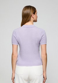 Lila polo shirt met korte mouwen van gestructureerde stof, kraag en slim fit ontwerp. De achterkant toont een gladde afwerking en een subtiel patroon.
