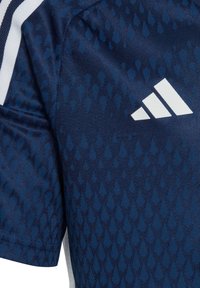 Marineblaue Sport-Trikot mit einem strukturierten Muster aus dunklen blauen Tropfen, ausgestattet mit einem weißen Adidas-Logo und Streifen auf der Schulter.