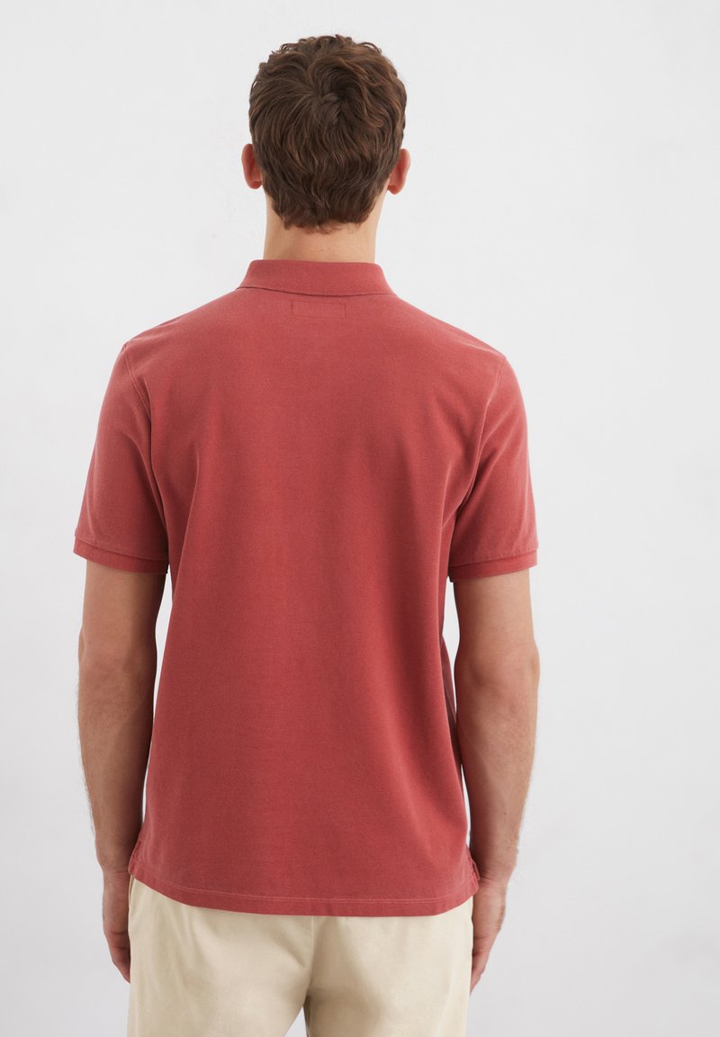 Rotes Baumwoll-Polohemd mit kurzen Ärmeln, ausgestattet mit einem klassischen Kragen und einem geraden Saum. Die Rückseite zeigt ein sauberes, einfaches Design ohne Grafiken.