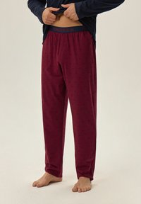 Burgundowe spodnie piżamowe z subtelnym granatowym wzorem, z elastycznym pasem oznaczonym "HENDERSON". Wykonane z miękkiego, lekkiego materiału.