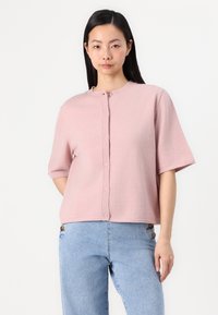 Cardigan rosa a maniche corte con scollatura rotonda, chiusura con bottoni e vestibilità rilassata. Il materiale sembra morbido con una finitura testurizzata.