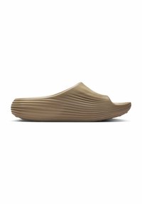 Sandalia beige tipo slip-on con un diseño suave y curvado y textura estriada en el lateral. Material de goma. Punta y parte trasera abiertas. Suela de perfil bajo.