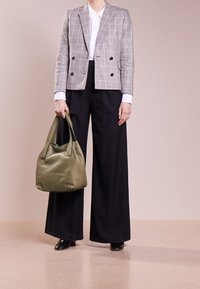 Szara kraciasta marynarka dwurzędowa, biała koszula, czarne spodnie z szerokimi nogawkami oraz zielona skórzana torba typu tote. Gładkie faktury i kontrastujące kolory.