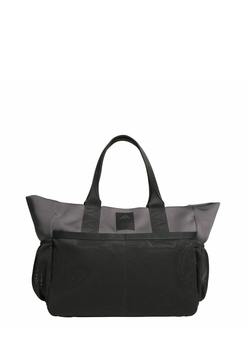 Šedá taška z mrežoviny s čiernymi doplnkami, vybavená dvoma pevnými rukoväťami, obdĺžnikovým tvarom a pevnou nášivkou s logom na prednej strane.